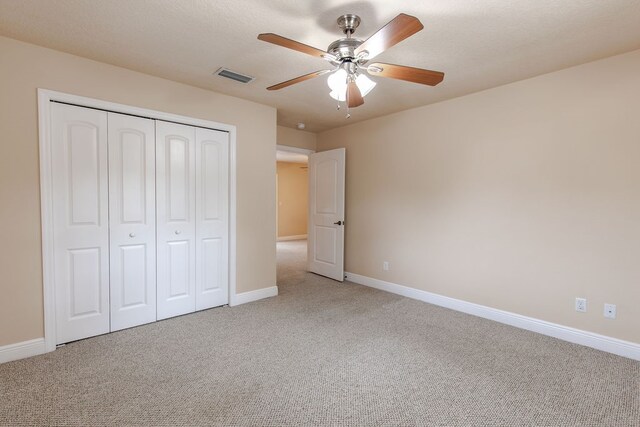 unfurnished bedroom featuring carpet floors, a closet, and ceiling fan