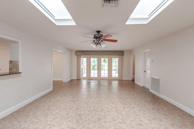 spare room with a skylight, ceiling fan, and french doors