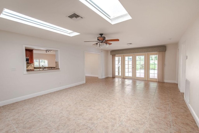 empty room with french doors, a skylight, and ceiling fan