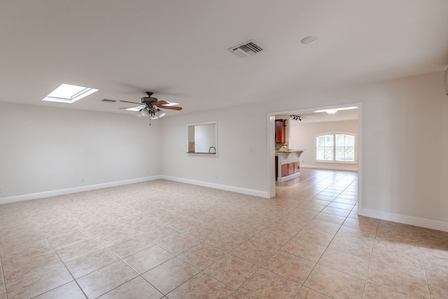 tiled empty room with a skylight and ceiling fan