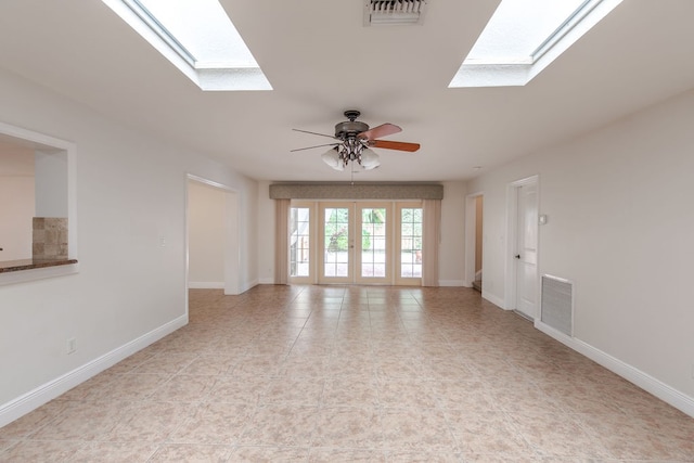 empty room with ceiling fan, a skylight, and french doors