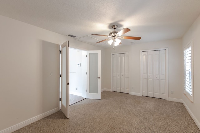 unfurnished bedroom featuring multiple windows, ceiling fan, and light colored carpet