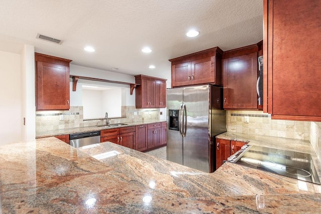 kitchen with light stone countertops, kitchen peninsula, backsplash, stainless steel appliances, and sink