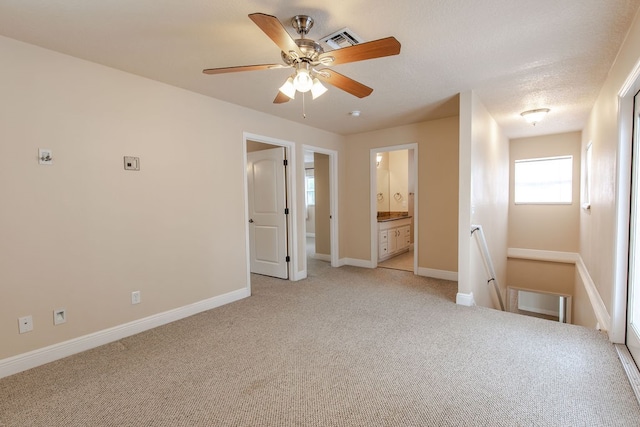 unfurnished bedroom featuring light carpet, connected bathroom, and ceiling fan