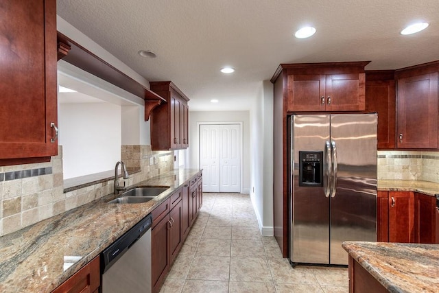 kitchen featuring backsplash, light stone countertops, sink, and appliances with stainless steel finishes