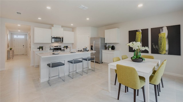 549 Benedictine Ter, Sebastian, FL 32958 - kitchen with stainless steel appliances, an island with sink, white cabinetry, a kitchen bar, and recessed lighting