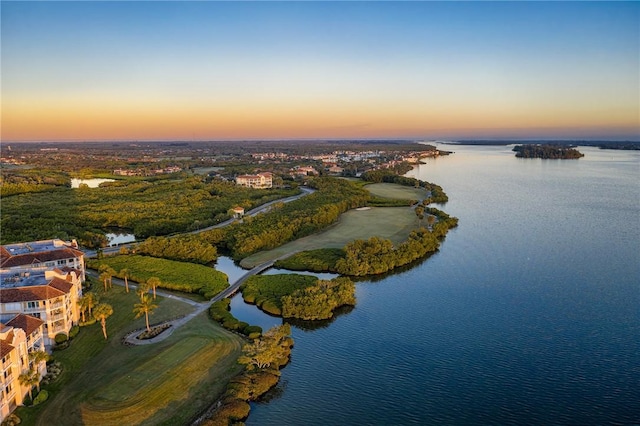 aerial view at dusk featuring a water view