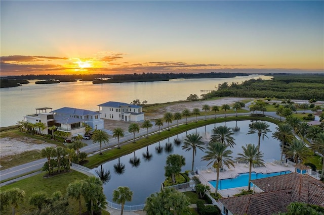 aerial view at dusk featuring a water view