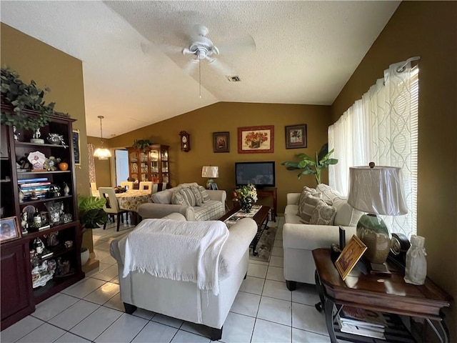 living room featuring lofted ceiling, light tile patterned floors, ceiling fan with notable chandelier, and a textured ceiling