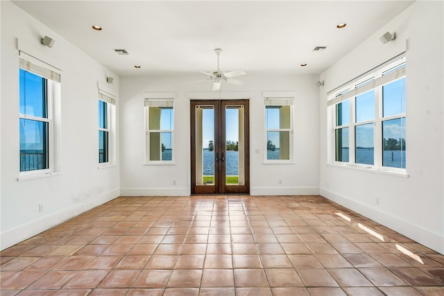 unfurnished room featuring a water view, french doors, light tile patterned floors, and ceiling fan