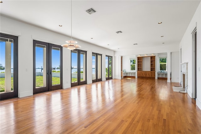 unfurnished living room featuring plenty of natural light, light wood-type flooring, and french doors