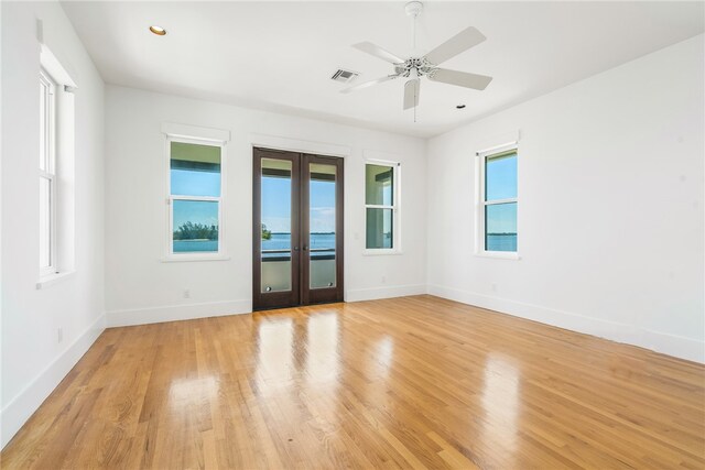 empty room featuring ceiling fan, light wood-type flooring, and french doors