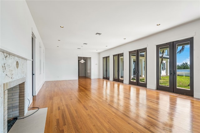 unfurnished living room featuring french doors and light hardwood / wood-style flooring