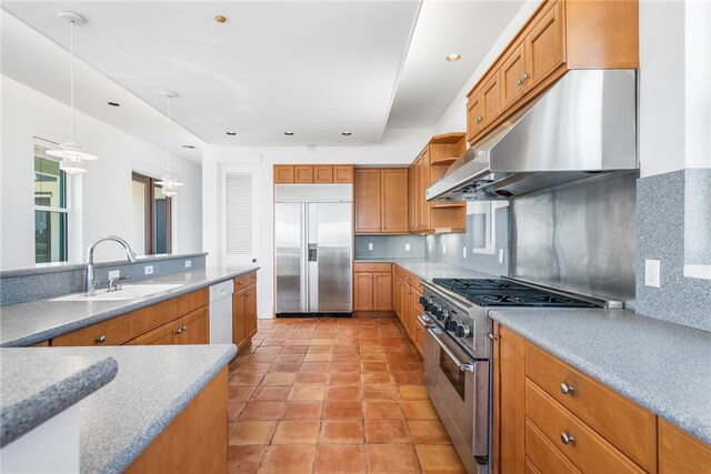 kitchen featuring tasteful backsplash, decorative light fixtures, exhaust hood, sink, and high end appliances