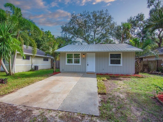 ranch-style home featuring central AC unit and a yard