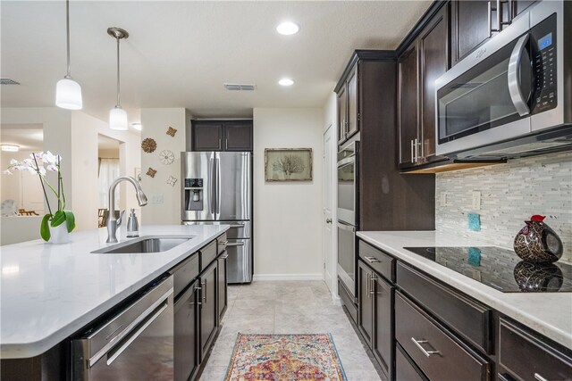 kitchen featuring sink, an island with sink, backsplash, pendant lighting, and appliances with stainless steel finishes