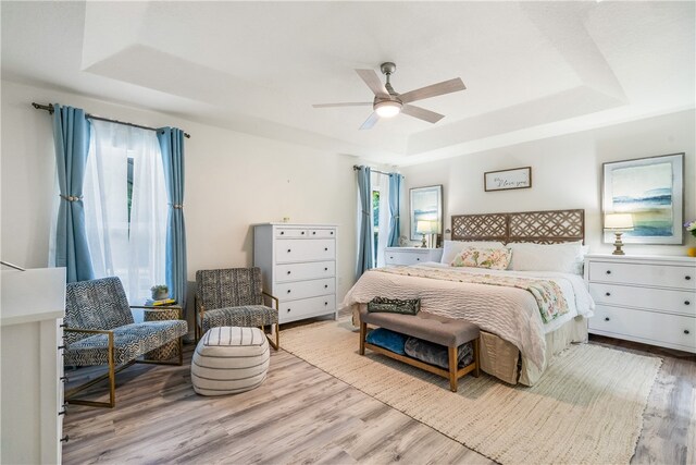 bedroom with ceiling fan, multiple windows, and a raised ceiling