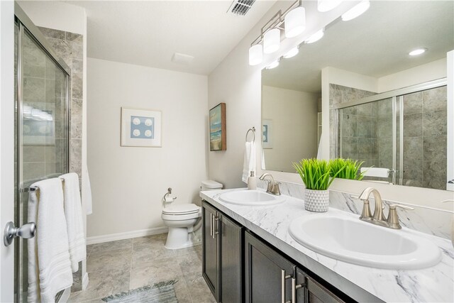 bathroom featuring toilet, vanity, and a shower with shower door