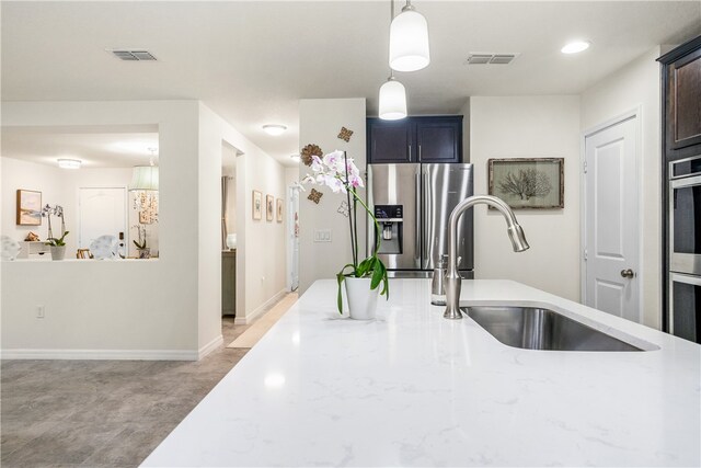 kitchen featuring light stone countertops, hanging light fixtures, sink, and stainless steel appliances