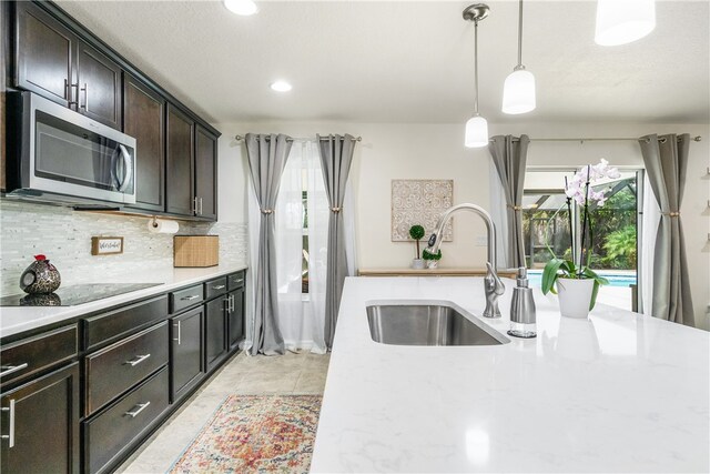 kitchen featuring tasteful backsplash, decorative light fixtures, dark brown cabinets, sink, and black electric cooktop