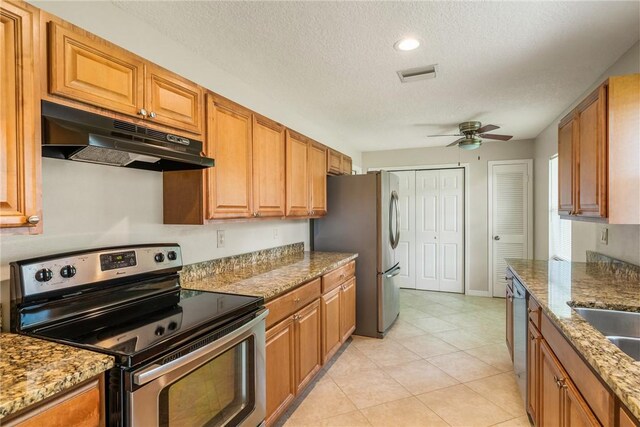 226 21st Ave, Vero Beach, FL 32962 - kitchen featuring stainless steel appliances, under cabinet range hood, ceiling fan, a textured ceiling, and light stone counters
