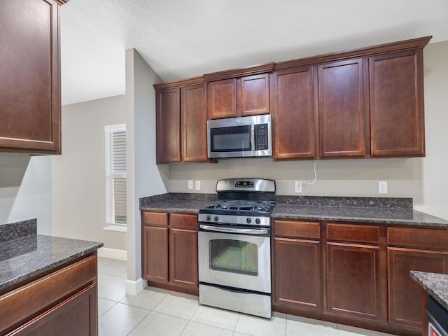 508 Calamondin Way SW, Vero Beach, FL 32968 - kitchen featuring dark stone counters, appliances with stainless steel finishes, light tile patterned floors, and baseboards
