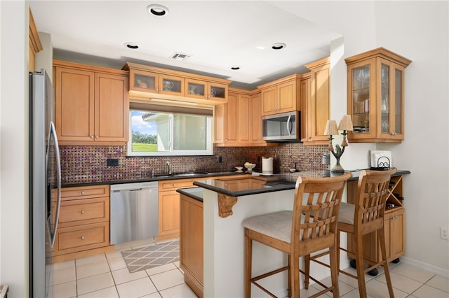 kitchen with a kitchen breakfast bar, sink, light tile patterned floors, and stainless steel appliances