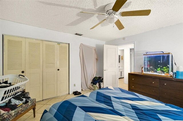 bedroom featuring light tile patterned floors, a textured ceiling, a closet, and ceiling fan