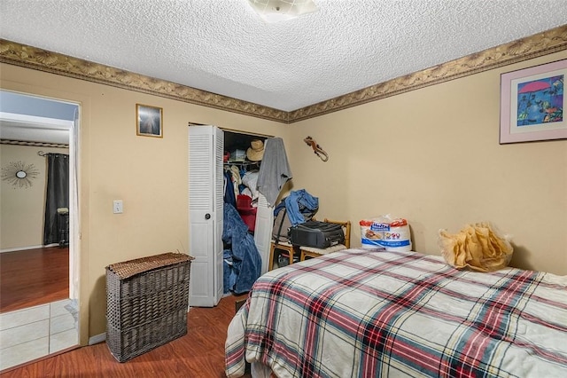 bedroom with hardwood / wood-style floors, a textured ceiling, and a closet