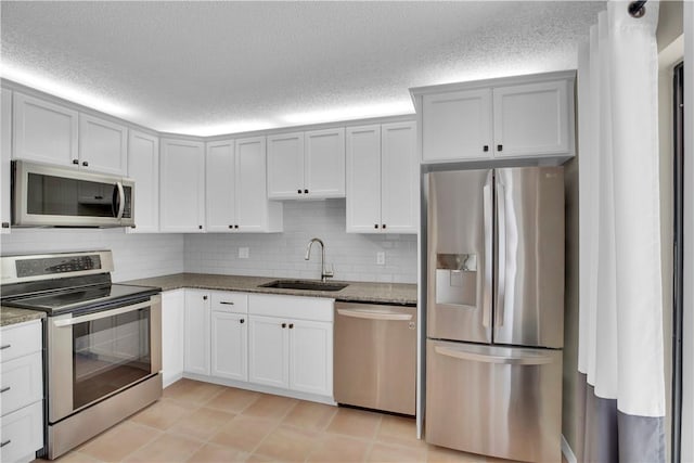 1011 Royal Palm Blvd Unit B3, Vero Beach, FL 32960 - kitchen with appliances with stainless steel finishes, backsplash, a textured ceiling, dark stone counters, and white cabinets