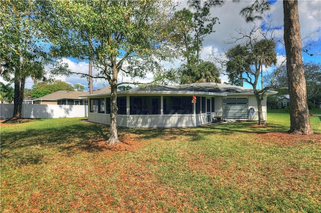 back of house featuring a lawn, fence, and a sunroom