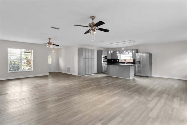 unfurnished living room featuring sink, track lighting, ceiling fan, and light hardwood / wood-style flooring