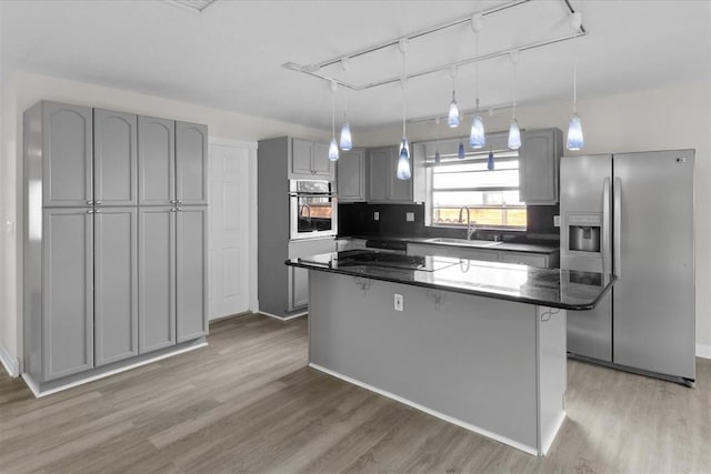 kitchen with sink, gray cabinetry, hanging light fixtures, stainless steel appliances, and a center island