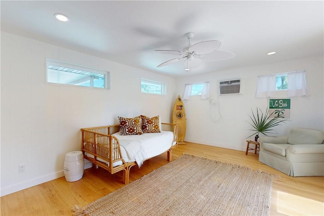 bedroom with multiple windows, hardwood / wood-style flooring, and a wall mounted AC