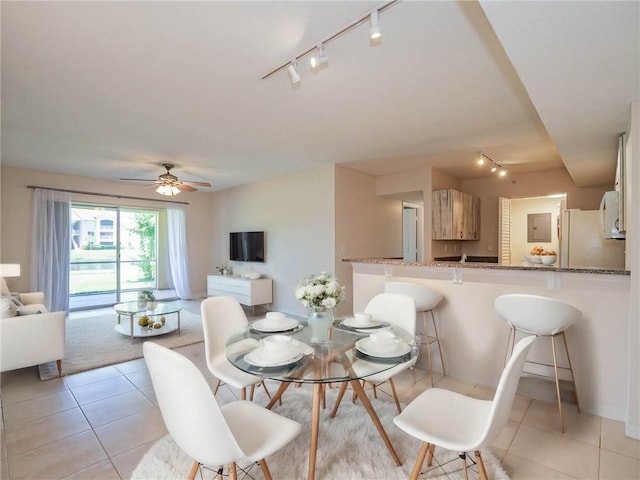 tiled dining room featuring rail lighting and ceiling fan