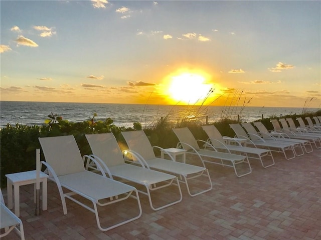 patio terrace at dusk featuring a water view