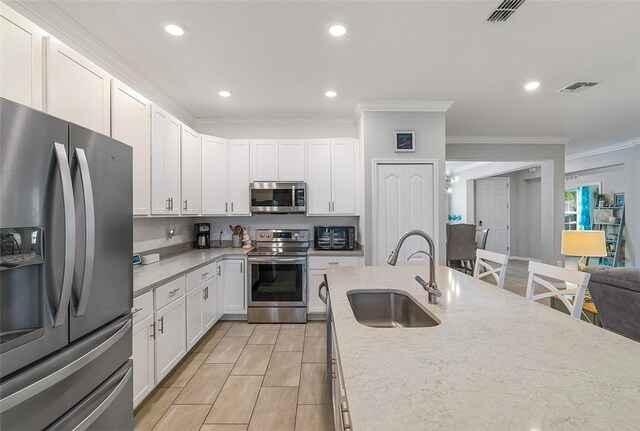 kitchen featuring crown molding, visible vents, appliances with stainless steel finishes, white cabinetry, and a sink