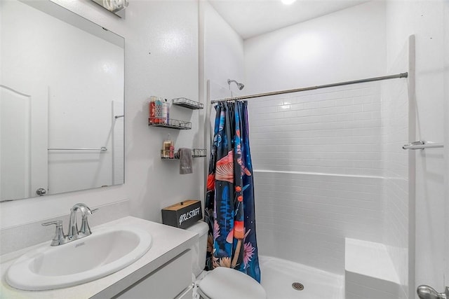 bathroom featuring vanity, a shower stall, and toilet