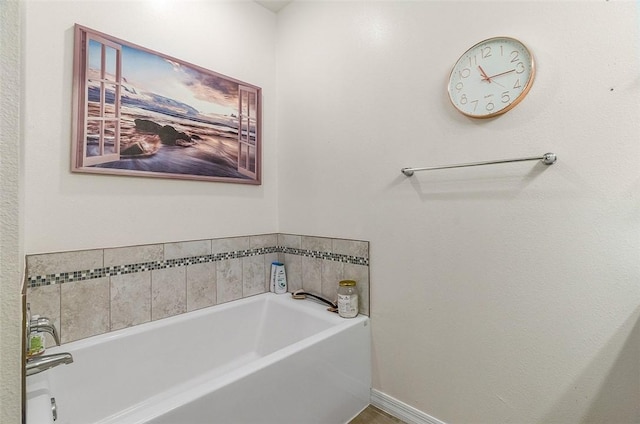 bathroom with a garden tub and baseboards