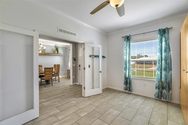 empty room featuring a textured ceiling, visible vents, baseboards, a ceiling fan, and ornamental molding