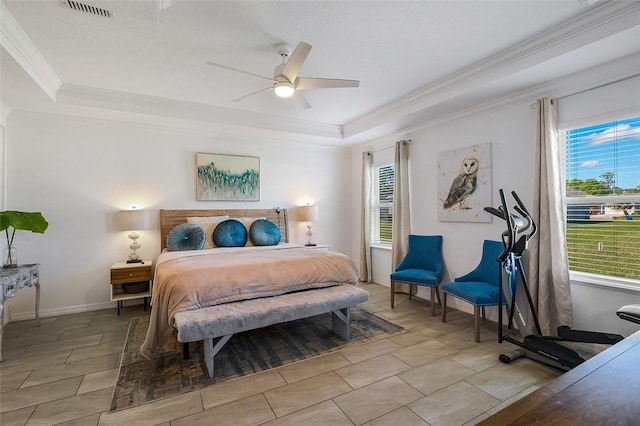 bedroom with ceiling fan, visible vents, baseboards, a tray ceiling, and crown molding