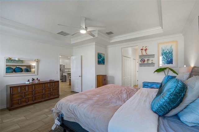 bedroom with wood finish floors, a raised ceiling, and visible vents