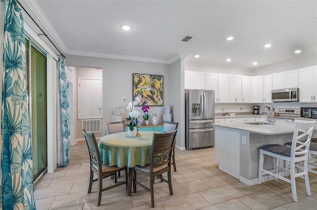 kitchen featuring a sink, white cabinets, light countertops, appliances with stainless steel finishes, and a center island with sink