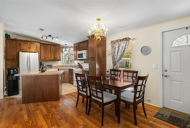 dining area with light wood finished floors, a toaster, visible vents, a textured ceiling, and a chandelier