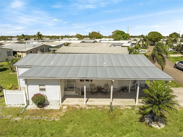 rear view of property featuring a residential view, metal roof, a patio, and fence