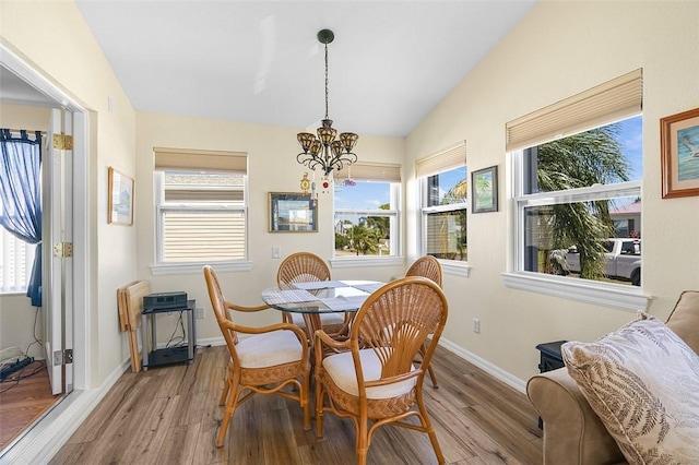 dining space featuring lofted ceiling, baseboards, an inviting chandelier, and wood finished floors