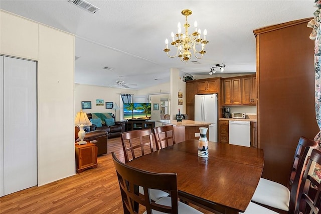 dining area with light wood-style floors, visible vents, vaulted ceiling, and ceiling fan with notable chandelier