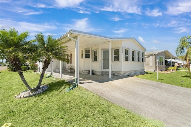 manufactured / mobile home featuring concrete driveway and a front lawn