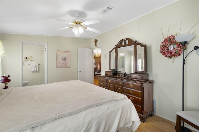 bedroom featuring light wood-style floors, visible vents, ensuite bath, and a ceiling fan