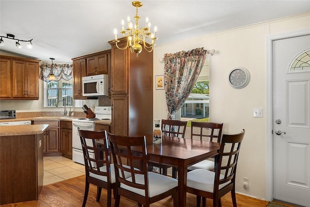 dining space featuring a toaster, light wood-style flooring, and a chandelier